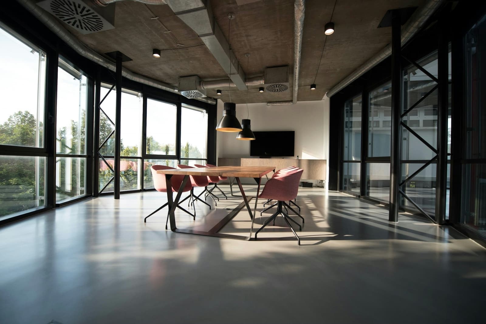 Sunlit boardroom with a wood table, chairs and floor-to-ceiling windows