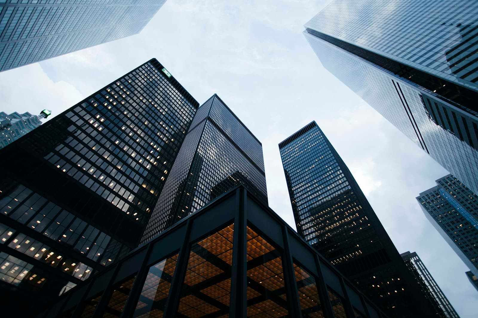 Looking up at glass office towers against a cloudy sky