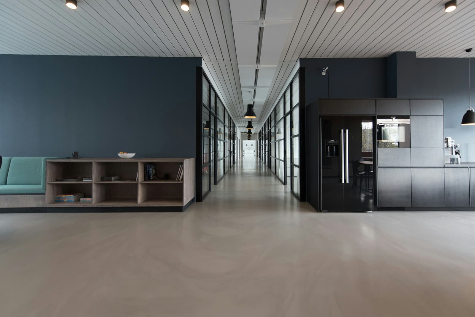 Quiet professional office corridor with glass meeting rooms and a navy lounge